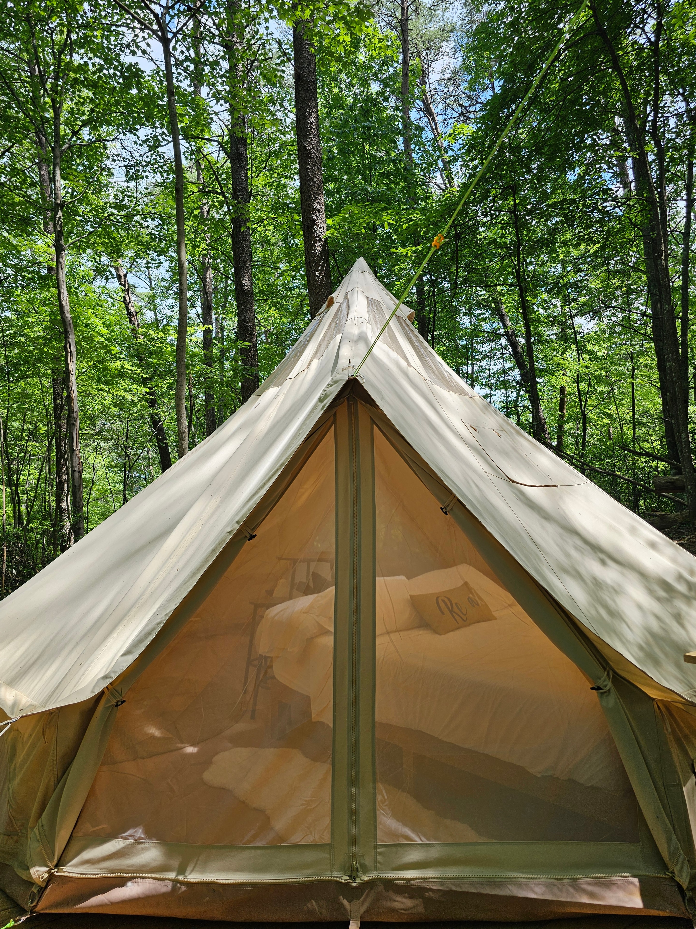 Cozy glamping tent interior with white linens and warm light